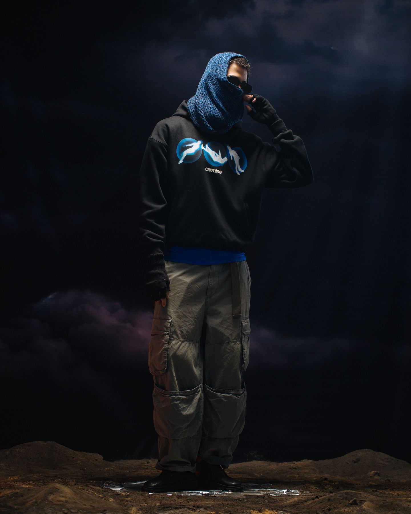 Model in a blue hood against storm clouds