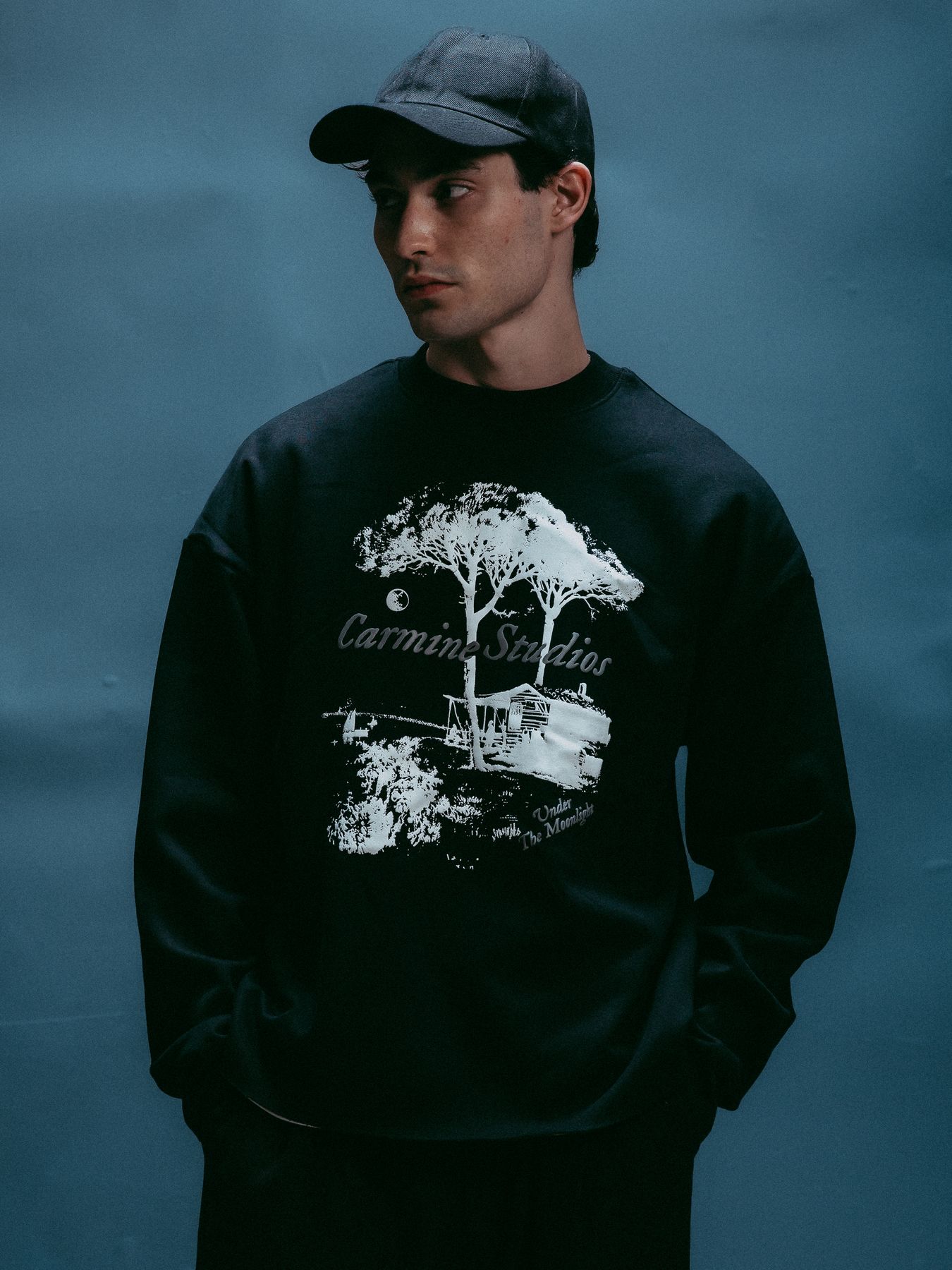 Model in a black tree-print sweatshirt and cap